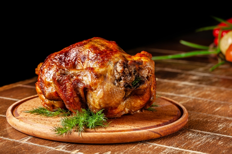 Chicken lies on a wooden board.