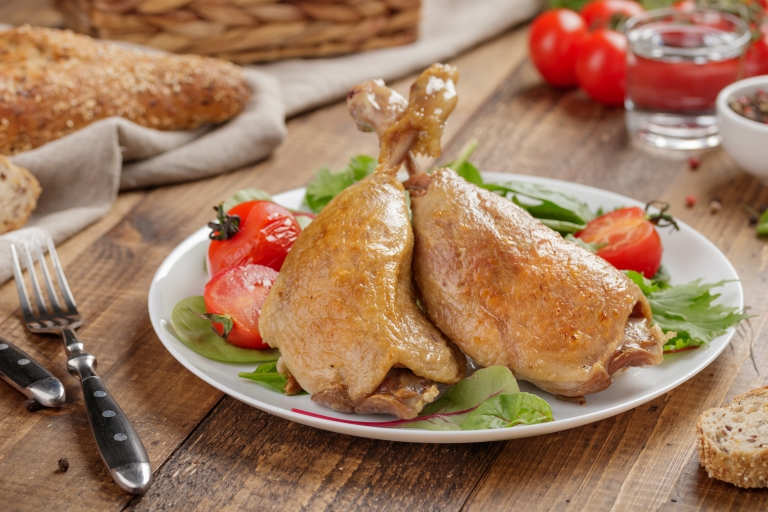 Duck chicken baked legs with vegetables on a wooden table